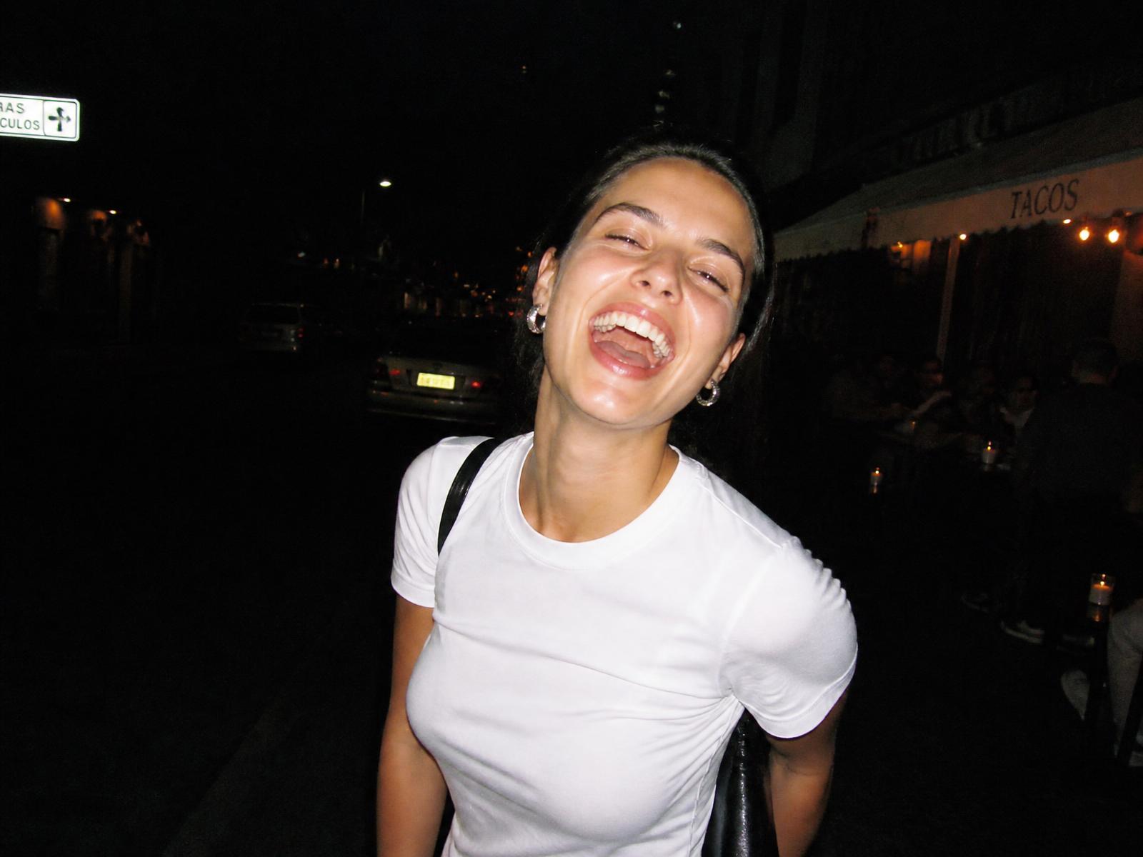 Flash photograph of a woman laughing outside a restaurant at night